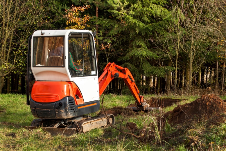 Red and white excavator commencing excavation work on site of new build in Swansea