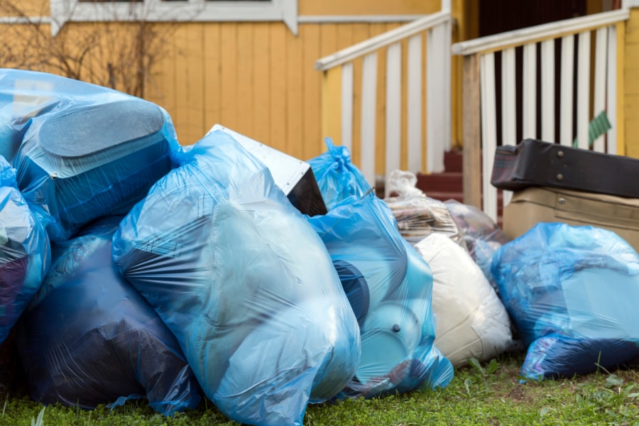 House clearance with Rubbish bags stacked outside a house in the front garden